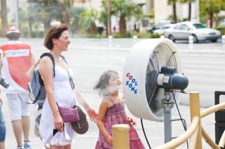 A mother and daughter pause for a brief moment in front of a misting fan during a hot day on the Strip. Tuesday, Aug. 21, 2012.